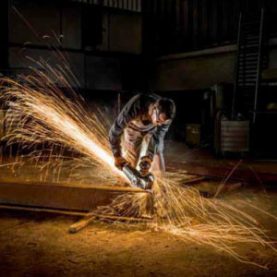 Man using angle grinder and Klingspor abrasive disk to cut railway sleeper